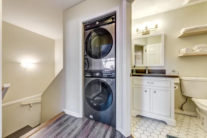 Laundry room featuring laundry area, a sink, stacked washer and clothes dryer, and baseboards