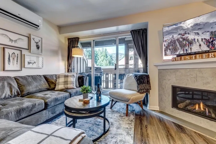 Living room featuring a fireplace, a wall unit AC, and wood finished floors