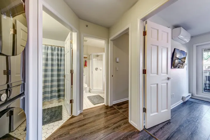 Hall featuring dark wood-type flooring, a wall mounted air conditioner, and baseboards
