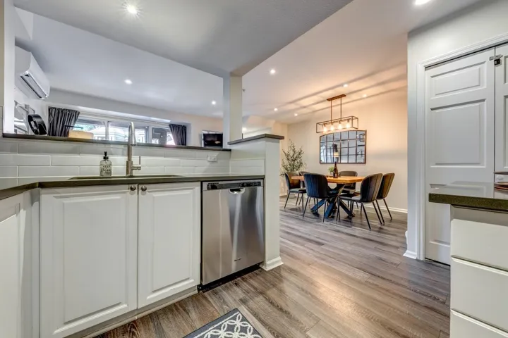 Kitchen with a sink, dark countertops, dishwasher, and a wall mounted AC