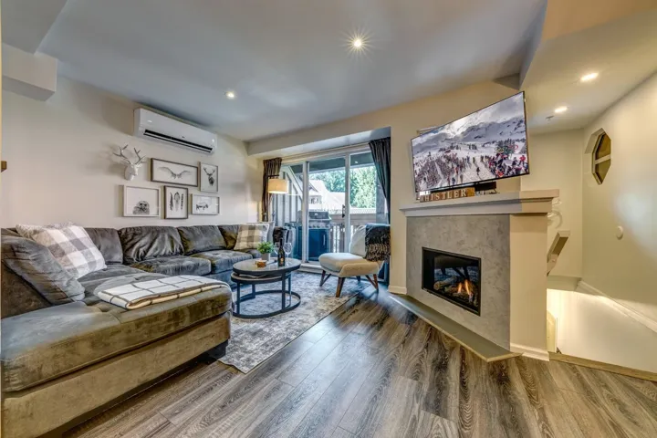Living area featuring an AC wall unit, a fireplace, wood finished floors, and recessed lighting