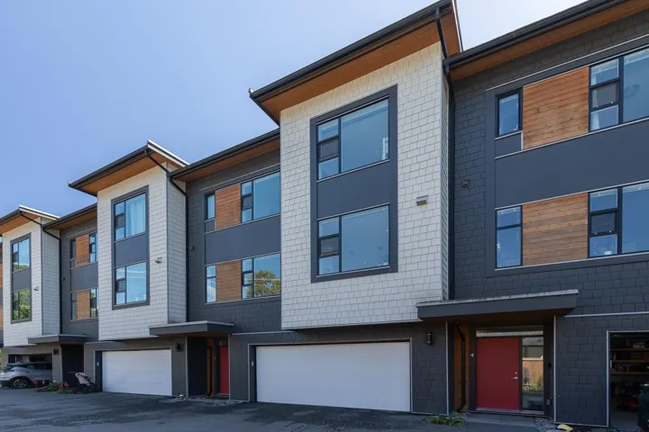 Contemporary multi-level townhome featuring a mixed-material facade with dark gray siding, light gray shingle accents, and natural wood paneling