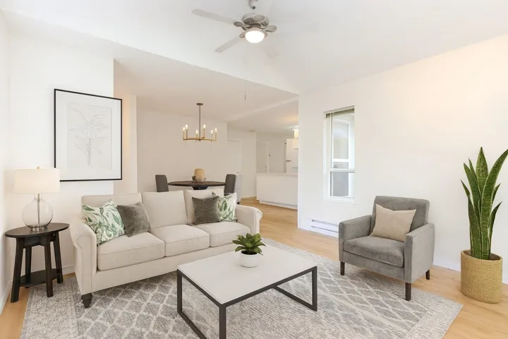 Living area with light wood finished floors, a chandelier, a baseboard heating unit, and a ceiling fan