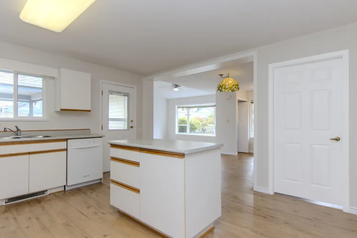 Kitchen featuring white cabinetry, white dishwasher, and light countertops