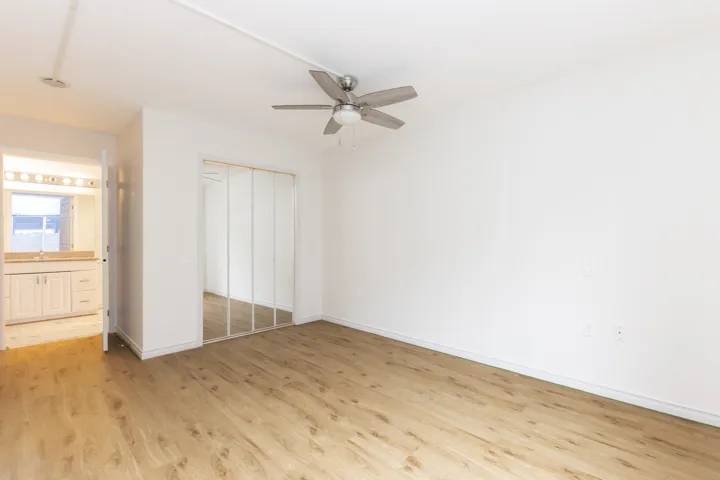 Unfurnished bedroom with light wood-type flooring, a closet, ensuite bathroom, and ceiling fan
