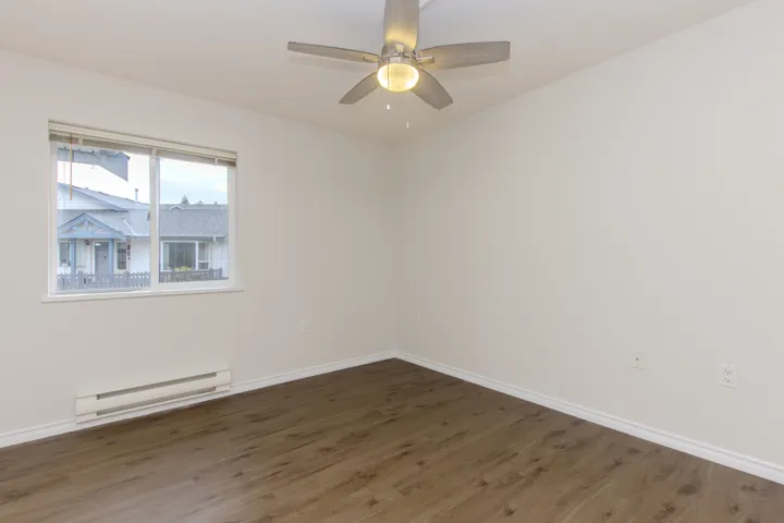 Empty room featuring a baseboard radiator, wood finished floors, and a ceiling fan