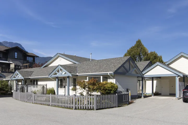 View of front facade featuring roof with shingles, a fenced front yard, driveway, and an attached carport