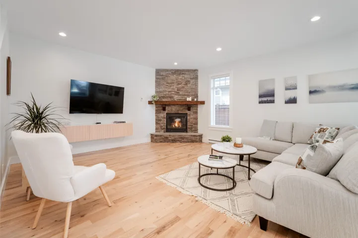 Living room with wood finished floors, recessed lighting, a fireplace, and baseboard heating