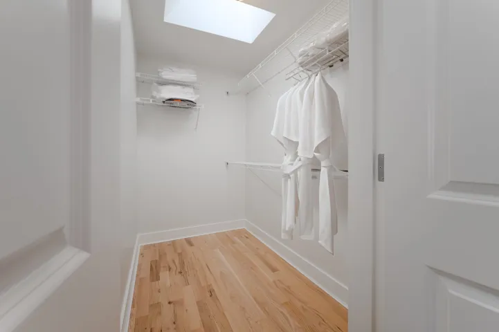 Walk in closet with a skylight and light wood-type flooring