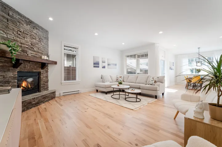 Living room with light wood finished floors, a baseboard heating unit, a fireplace, baseboards, and recessed lighting
