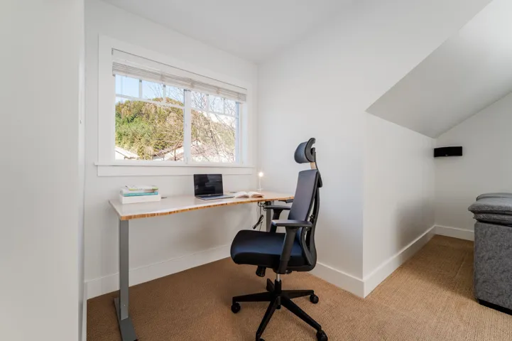 Carpeted office space with baseboards and lofted ceiling