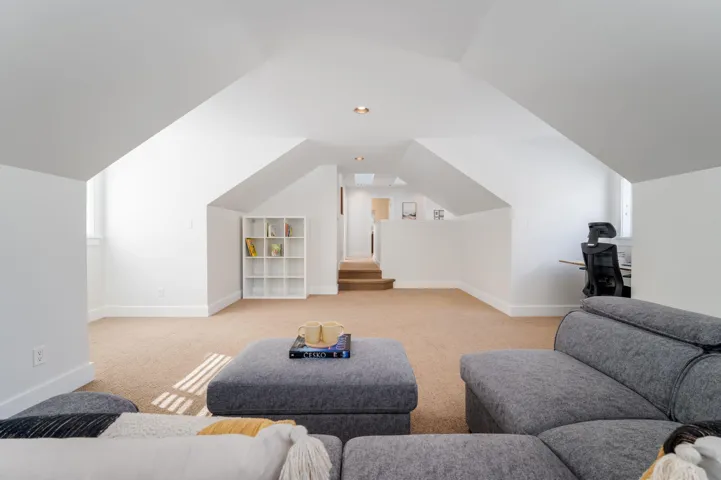 Living room featuring carpet flooring, baseboards, and vaulted ceiling