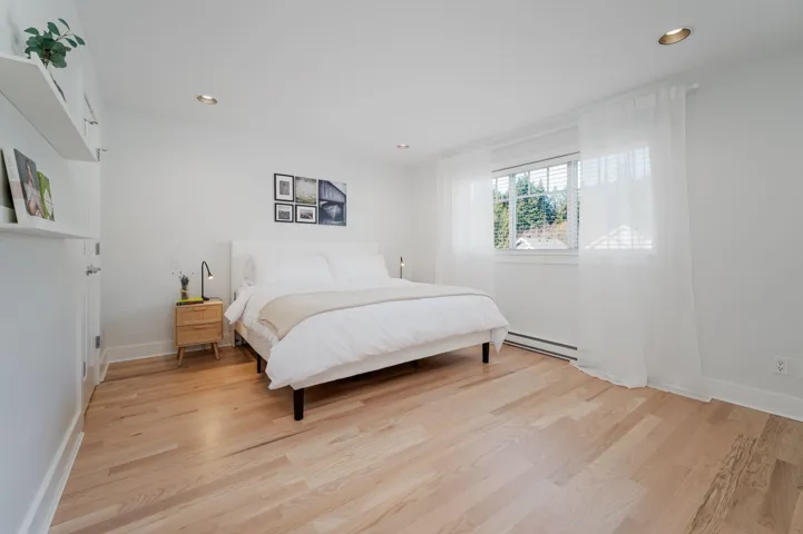 Bedroom featuring a baseboard heating unit, light wood-style floors, baseboards, and recessed lighting