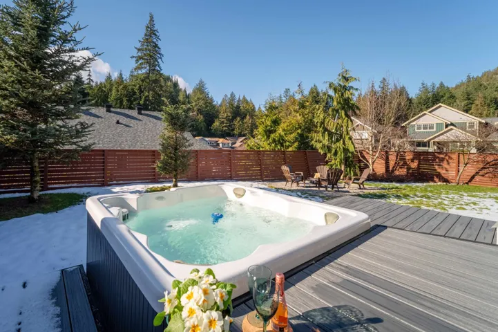 View of pool featuring an outdoor hot tub, a deck, and a fenced backyard