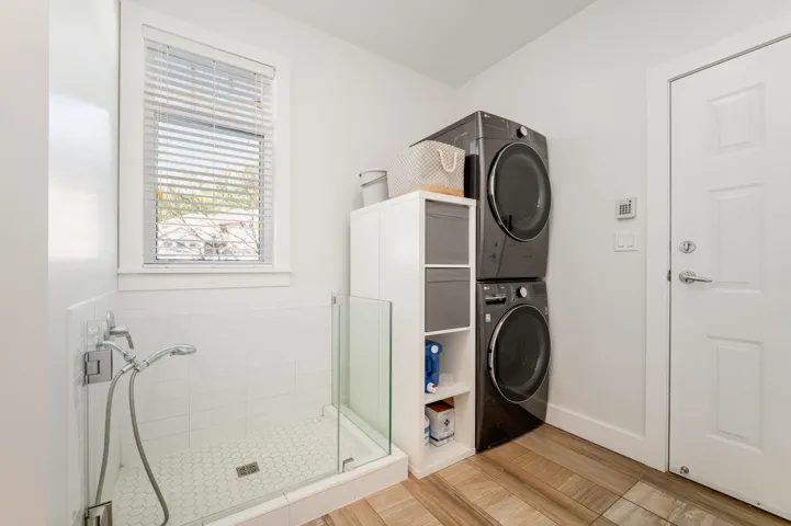 Full bath with estacked washer and dryer and a stall shower