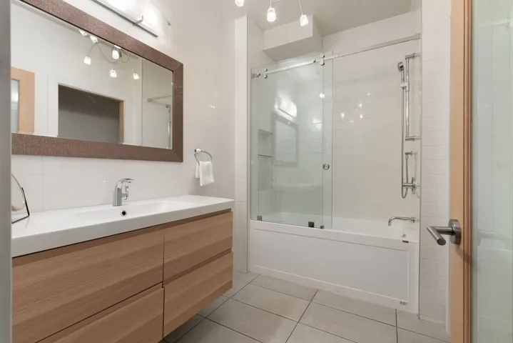 Full bathroom featuring vanity, combined bath / shower with glass door, decorative backsplash, light tile patterned floors, and tile walls