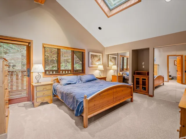 Large primary bedroom with ensuite, vaulted ceilings, skylight and a private deck.