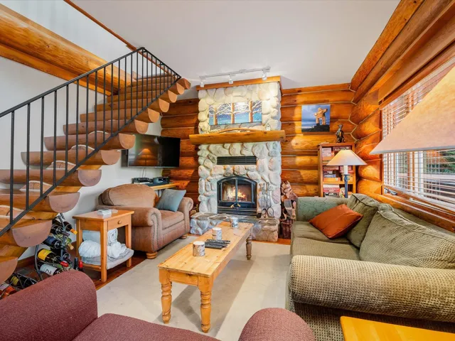 Sunny living room with wood burning fireplace, open floor plan kitchen and dining area.