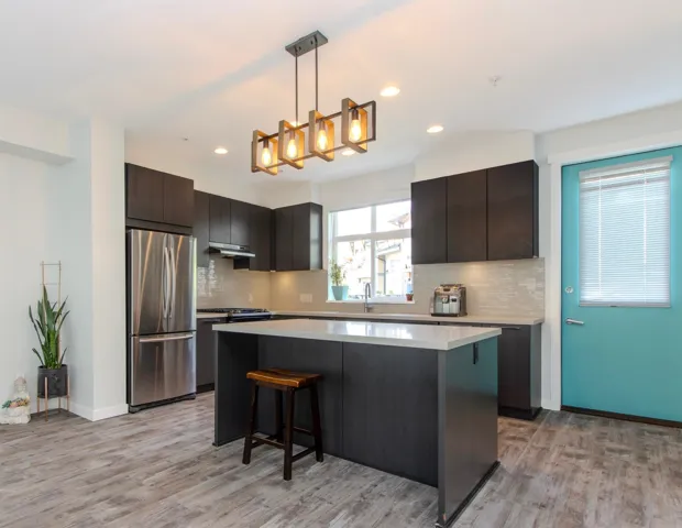 Kitchen featuring a breakfast bar, appliances with stainless steel finishes, pendant lighting, a center island, and backsplash