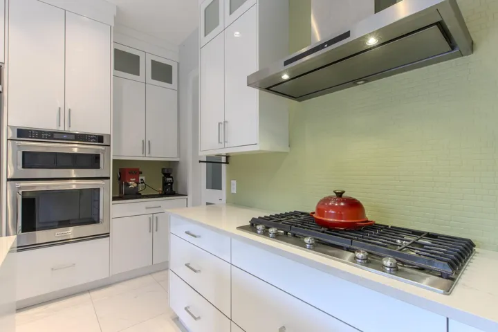 Kitchen featuring extractor fan, stainless steel appliances, white cabinetry, and tasteful backsplash