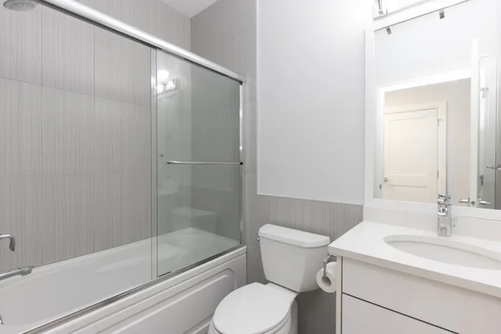 Bathroom with a wainscoted wall, vanity, and shower / bath combination with glass door
