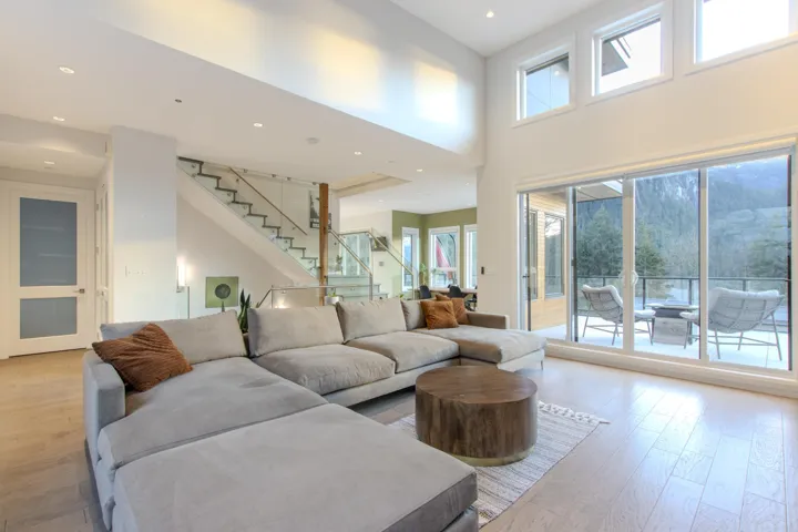 Living area featuring light wood-style flooring, a high ceiling, recessed lighting, and stairs