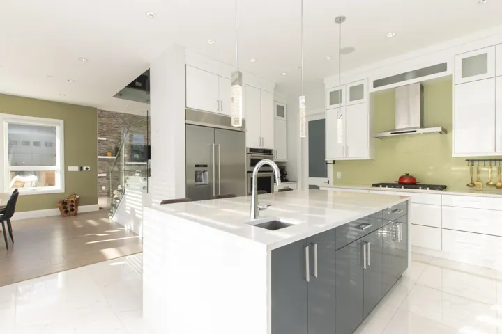 Kitchen featuring a kitchen island with sink, appliances with stainless steel finishes, light marble finish floors, white cabinetry, and recessed lighting