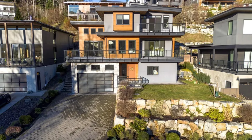 View of front of house featuring a balcony, decorative driveway, a front lawn, and a garage