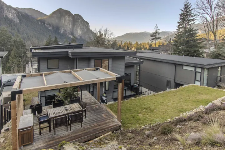 Rear view of property with a deck with mountain view, outdoor dining space, and a yard