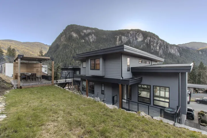 Back of property featuring a deck with mountain view and a lawn