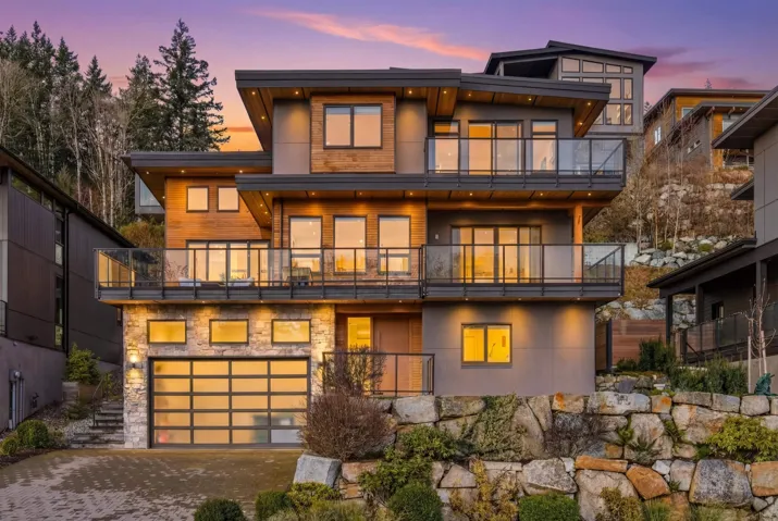 View of front of house featuring driveway, a balcony, and an attached garage