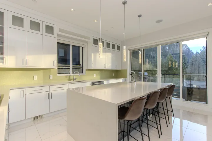 Kitchen with a center island with sink, glass insert cabinets, white cabinets, a kitchen breakfast bar, and recessed lighting