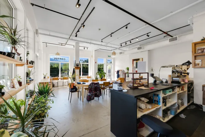 Spacious open-concept interior featuring large windows, high ceilings, track lighting, and light-toned flooring