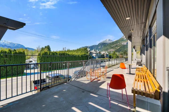 Spacious outdoor patio featuring a concrete surface, black metal railing, and an overhead awning with recessed lighting