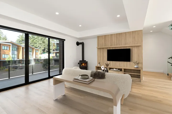 Living area featuring a wood stove, recessed lighting, a raised ceiling, and light wood-style floors