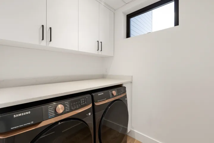Laundry area with washer and dryer, wood finished floors, and cabinet space