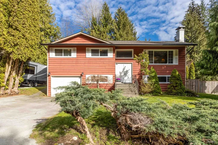 Split foyer home featuring an attached garage, a chimney, fence, a front lawn, and driveway