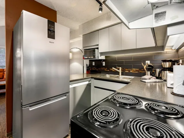 Kitchen with appliances with stainless steel finishes, dark countertops, gray cabinets, backsplash, and a textured ceiling