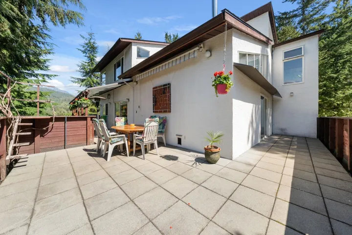 Expansive outdoor patio featuring large square pavers, a wood-paneled privacy fence, and a white stucco exterior