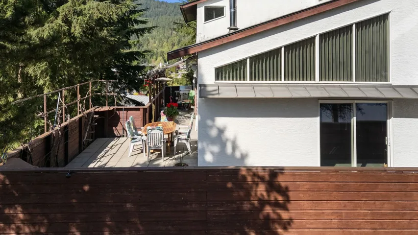 Wood-finish deck with a partial wooden railing and a white stucco exterior