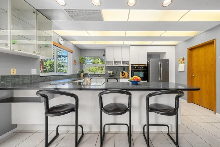 Kitchen featuring a central island with a dark countertop, white cabinetry, integrated appliances, and recessed lighting