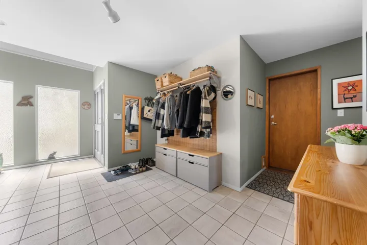 Entryway featuring light-toned tile flooring and a built-in storage bench with overhead shelving