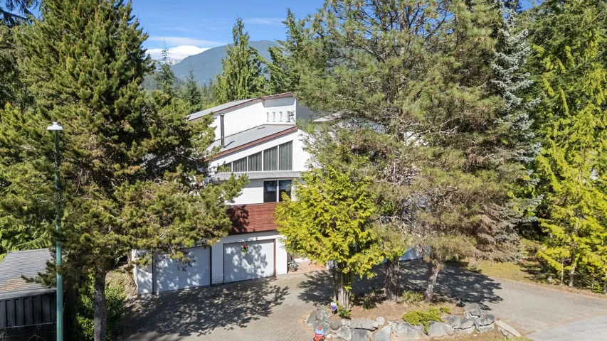 Contemporary architecture featuring multiple rooflines, a two-car garage, and extensive natural landscaping