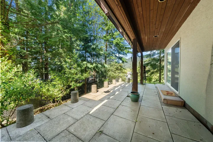 Expansive outdoor patio featuring large format pavers, a wood-paneled ceiling, recessed lighting, and a sliding glass door