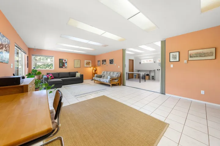 Spacious interior featuring tile flooring, ample natural light from multiple windows and ceiling fixtures, and a folding partition door opening to an additional room
