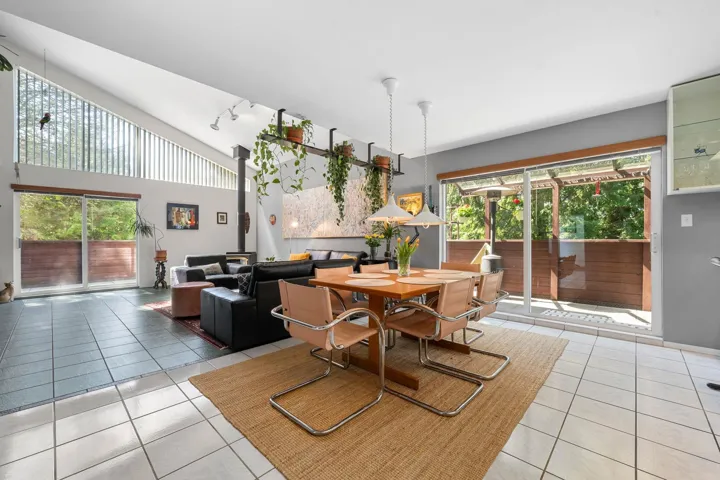 Open-concept living and dining area with vaulted ceilings and exposed structural beams