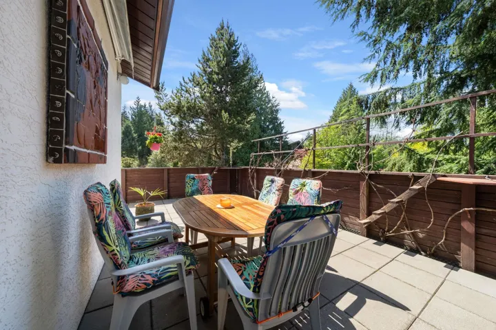 Outdoor patio featuring large format paver tiles, a wooden privacy fence, and an ornate metal railing