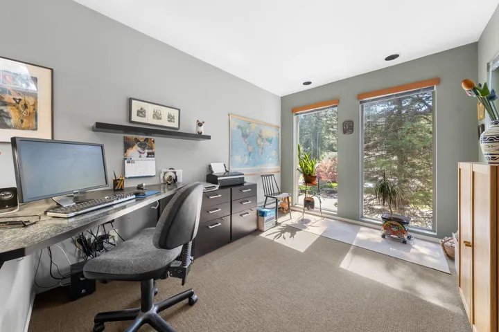 Spacious room featuring two large windows, recessed ceiling lighting, wall-to-wall carpeting, and a built-in desk with extensive counter space