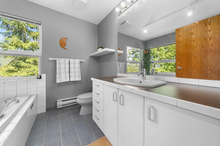 Bathroom featuring a wide vanity with integrated sink, white cabinetry, and an expansive mirror