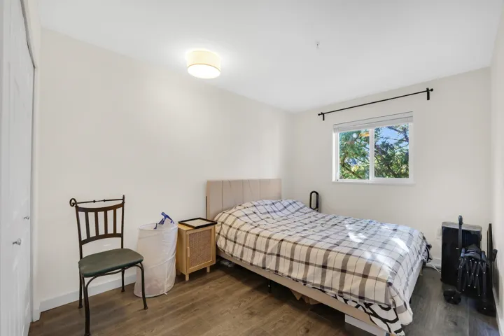 Bedroom featuring wood-finish flooring, a neutral color palette, recessed flush-mount lighting, and a window with a rod-mounted curtain bracket